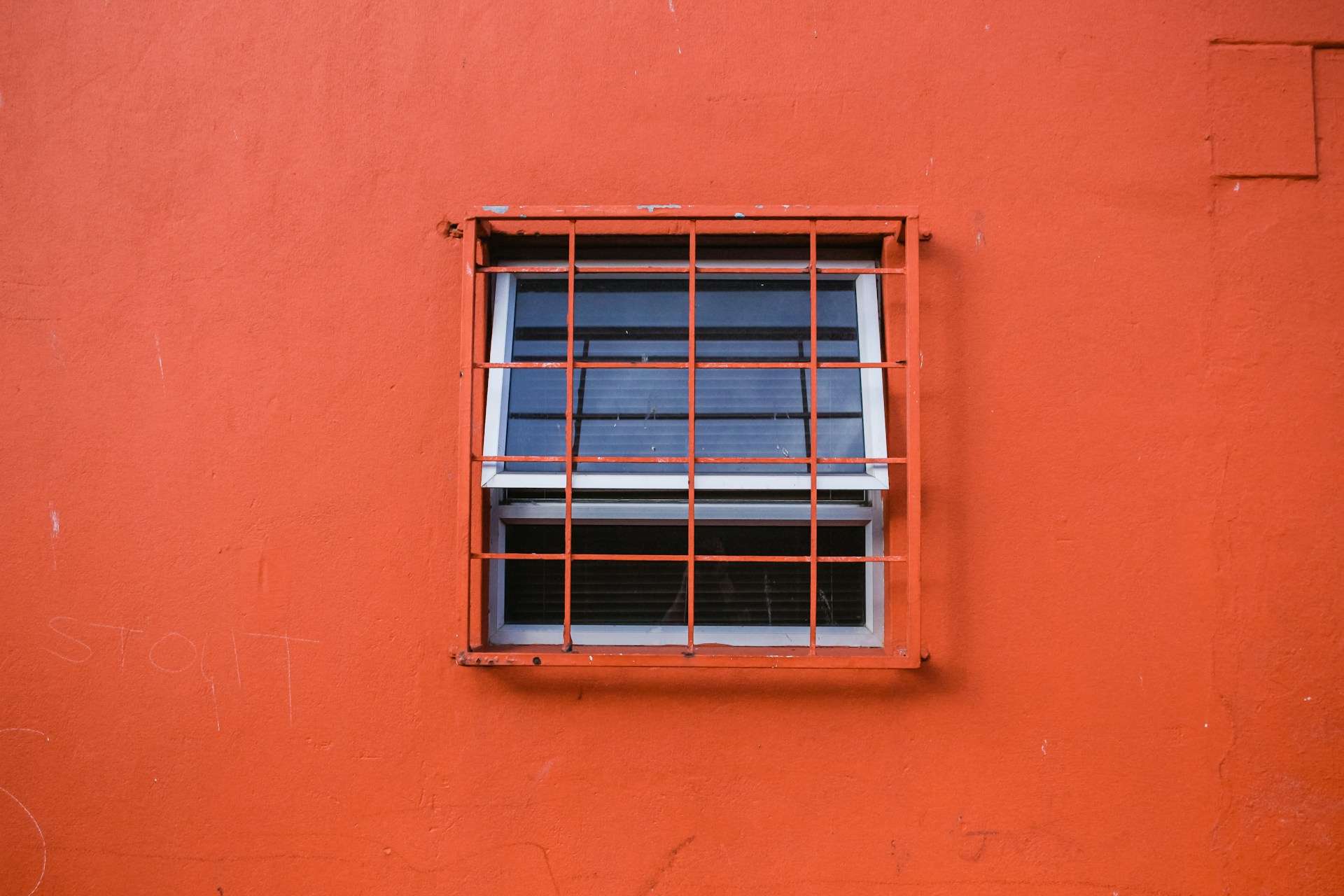 A barred window in a red wall