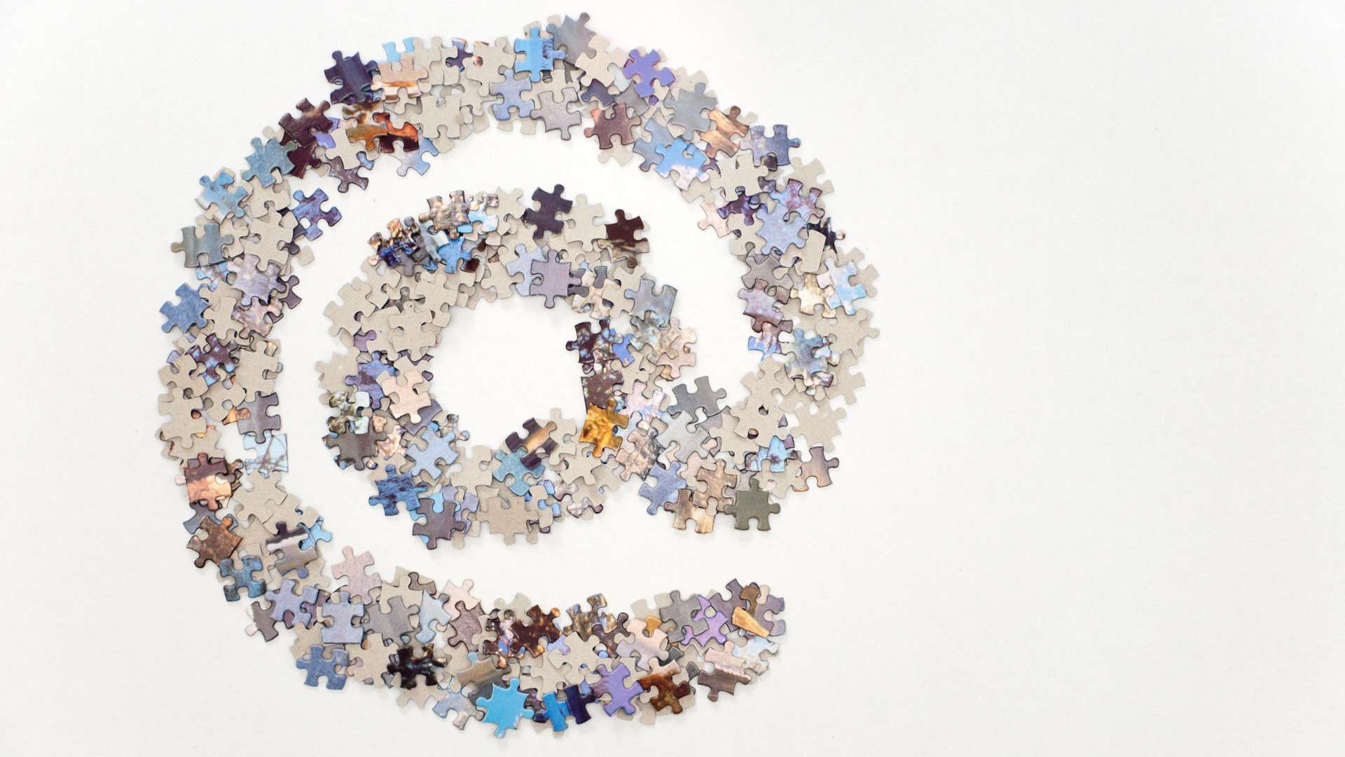 Large @ (arond) sign used for email, made from lots of jigsaw puzzle pieces and separated on a white background