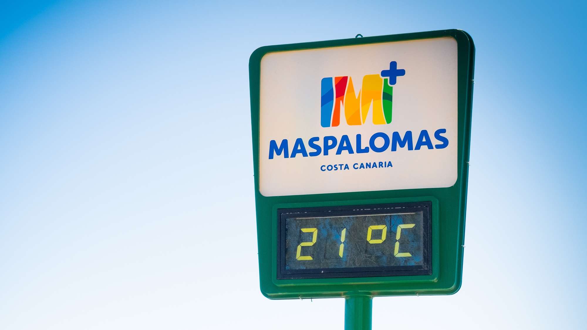 A large sign saying 'Maspalomas, Cosa Canaria' with the current temperature '21 °C'